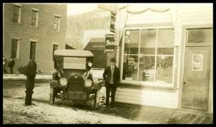 Mr. Curtis and automobile in front of Curtis Transfer office, 1st Street East