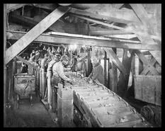 Mine workers picking from conveyor belt of ore underground
