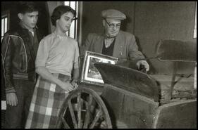 [Group examining old wagon]