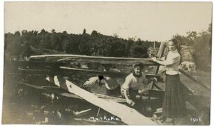Three young women climbing through a wooden rail fence in Muskoka