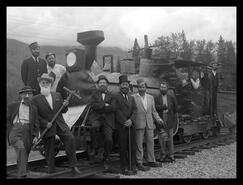 Group of men in front of train engine at Malakwa Craigellachie Spike Day