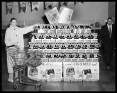 Woman and Bob Hutchinson beside the McCulloch's Aerated Waters Ltd. Coca-Cola display at Safeway