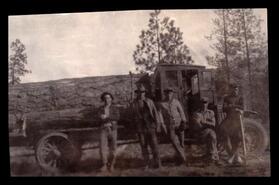 Five men in front of a logging truck with a very large log on its deck