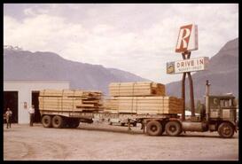 Truck load of lumber next to R-Drive In sign near junction of Trans Canada Highway