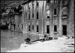 Man sitting in a boat on Groutage Avenue during 1948 flood
