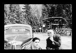 Two men beside a car by New Denver Japanese internment camp gate