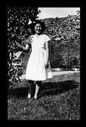 Unidentified woman in a white dress beside a tree