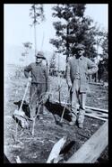 William Swanson and Arthur Fraser cleaning yard with axes