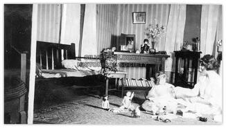 Women and girl playing with dolls and toys in sitting room