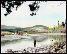 Hand coloured  photograph of the  South Thompson River with two men fishing