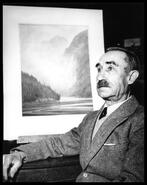 Local artist and photographer C.W. Holliday sitting in front of a painting