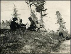 Four men eating by camp fire during lunch break